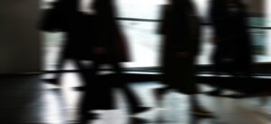Abstract blurred motion of people walking indoors, depicting urban life and busy routines.