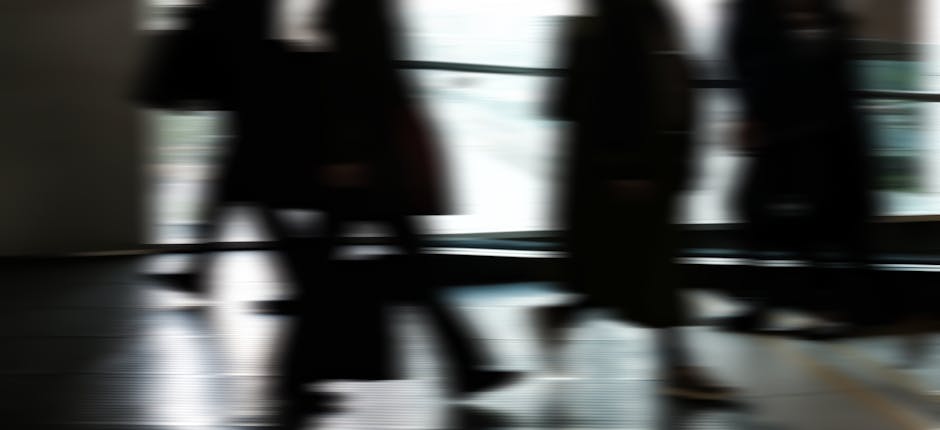 Abstract blurred motion of people walking indoors, depicting urban life and busy routines.