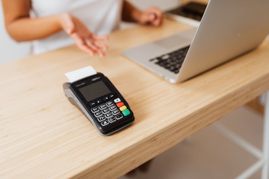 Close-up of a card reader on a wooden desk ready for contactless payment.