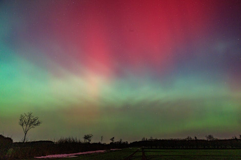 Vibrant Northern Lights in colorful hues fill the night sky above serene landscape.