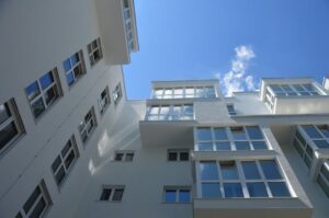 Low angle view of a modern, white building against a clear blue sky, showcasing contemporary architecture.
