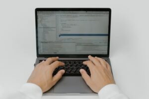 Close-up of hands coding on a laptop, showcasing software development in action.