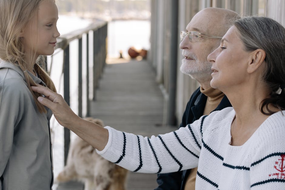 Grandparents enjoying a moment with their granddaughter outdoors on a dock.